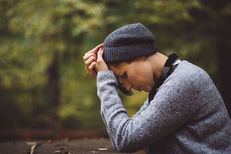 woman sad, stressed, touching her hand showing warning signs of addiction